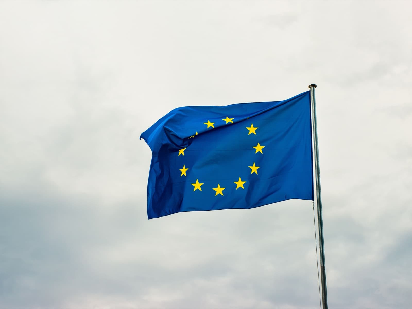 De vlag van de Europese Unie wappert tegen een bewolkte lucht.